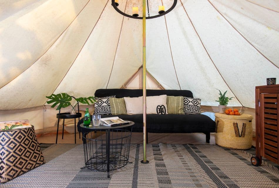 Interior of a glamping tent with a couch, rug, wood rolling cart and coffee table