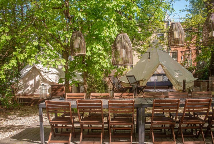 Serene backyard with two glamping tents, each on its own deck, with large dining table with wood chairs