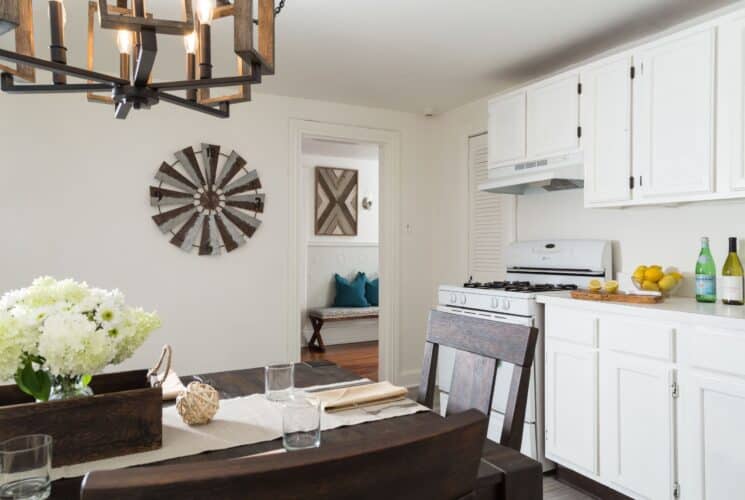 Kitchen area with stove, white cabinets, dark wood dining table and chairs and doorway into a hallway