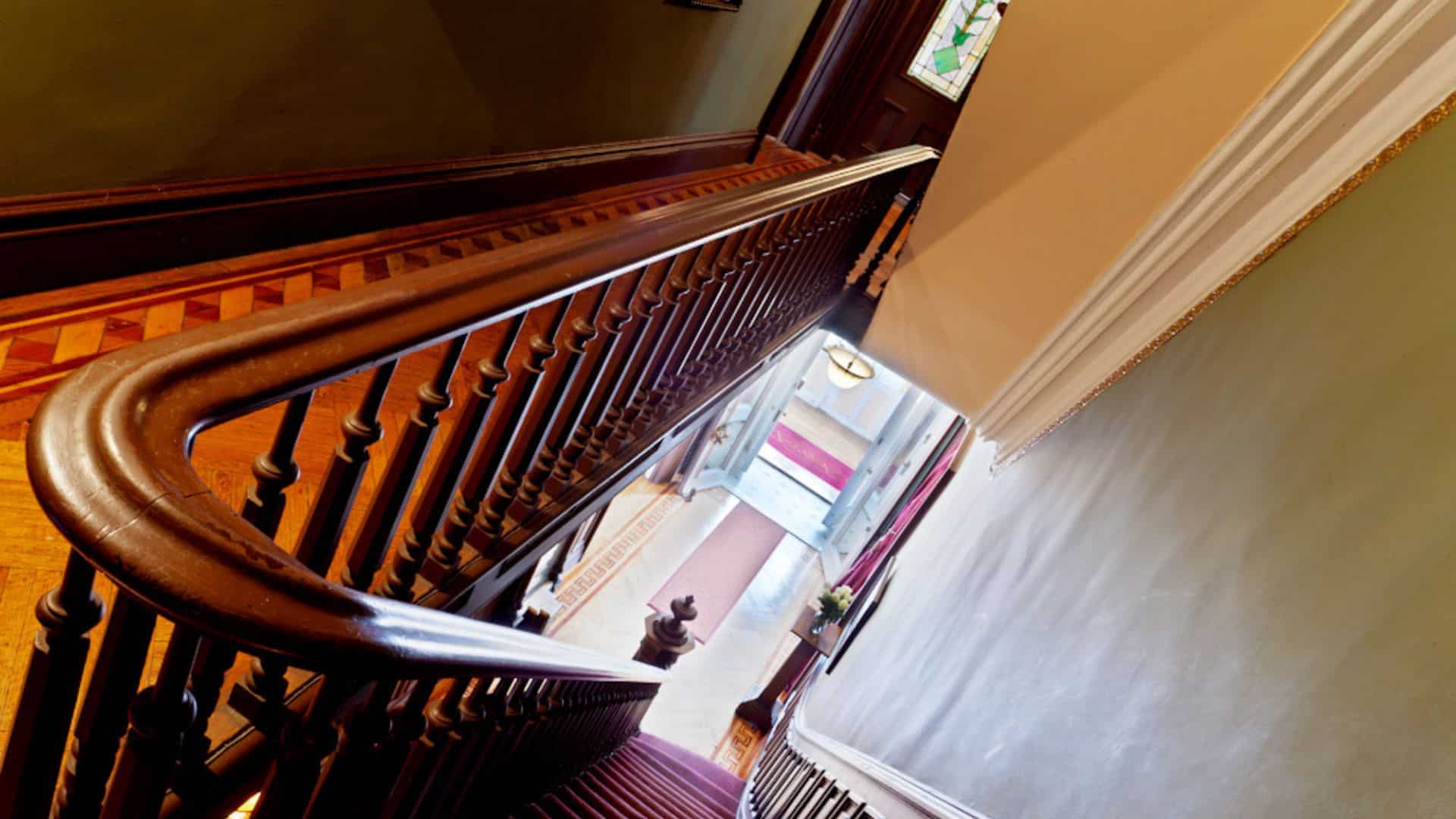 Gorgeous curved banister railing at the top of a narrow staircase