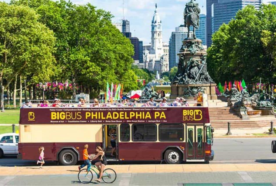 Downtown city street with a city bus, statue and skyline behind